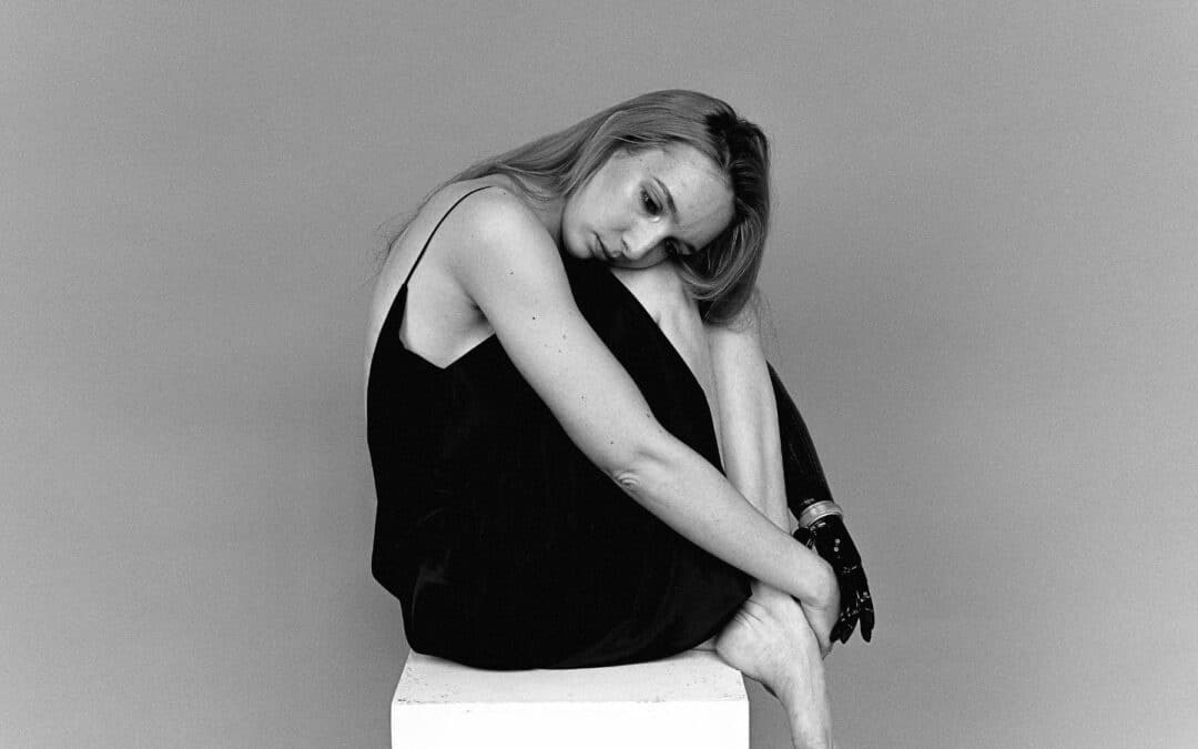 A girl sitting quietly on a chair, looking thoughtful, reflecting on struggles with short-term disability and mental health issues